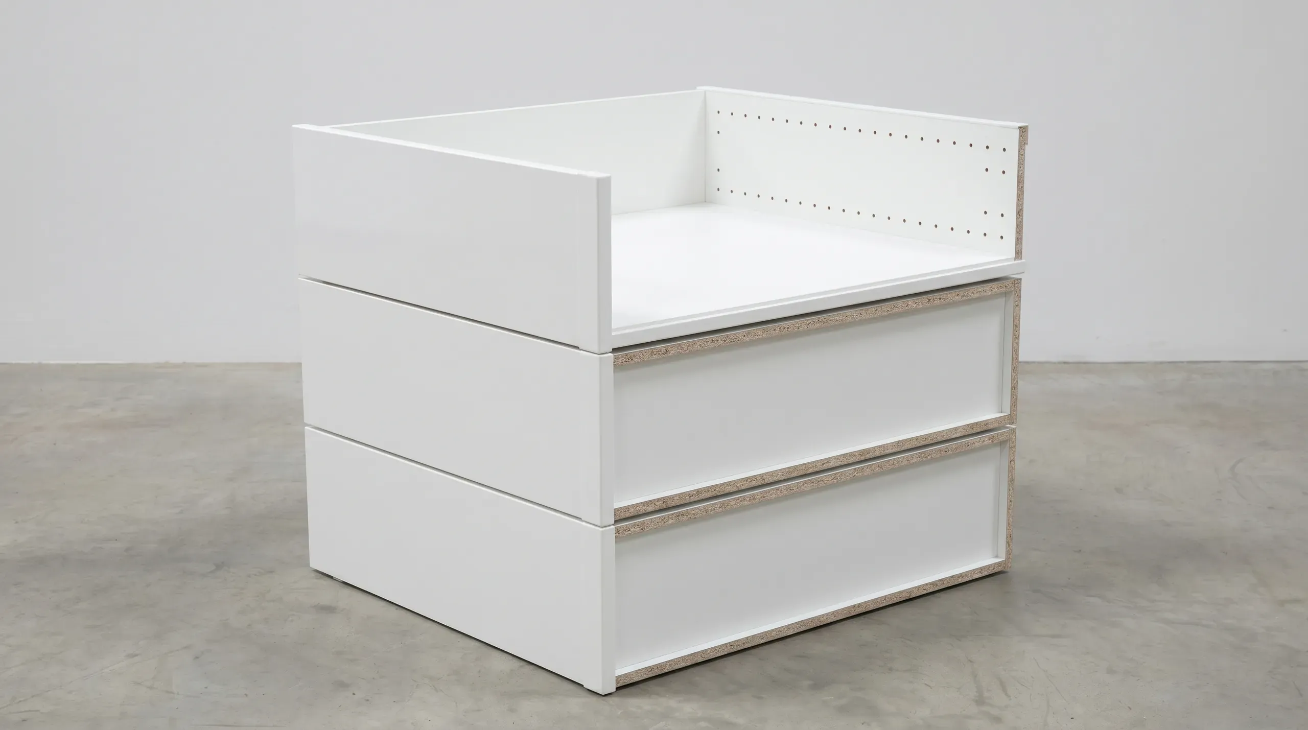 A stack of rigid pre-assembled kitchen unit carcasses in 18mm MFC with 2mm ABS front edgebanding visible on the exposed edges, stored in a fabricator's warehouse before delivery