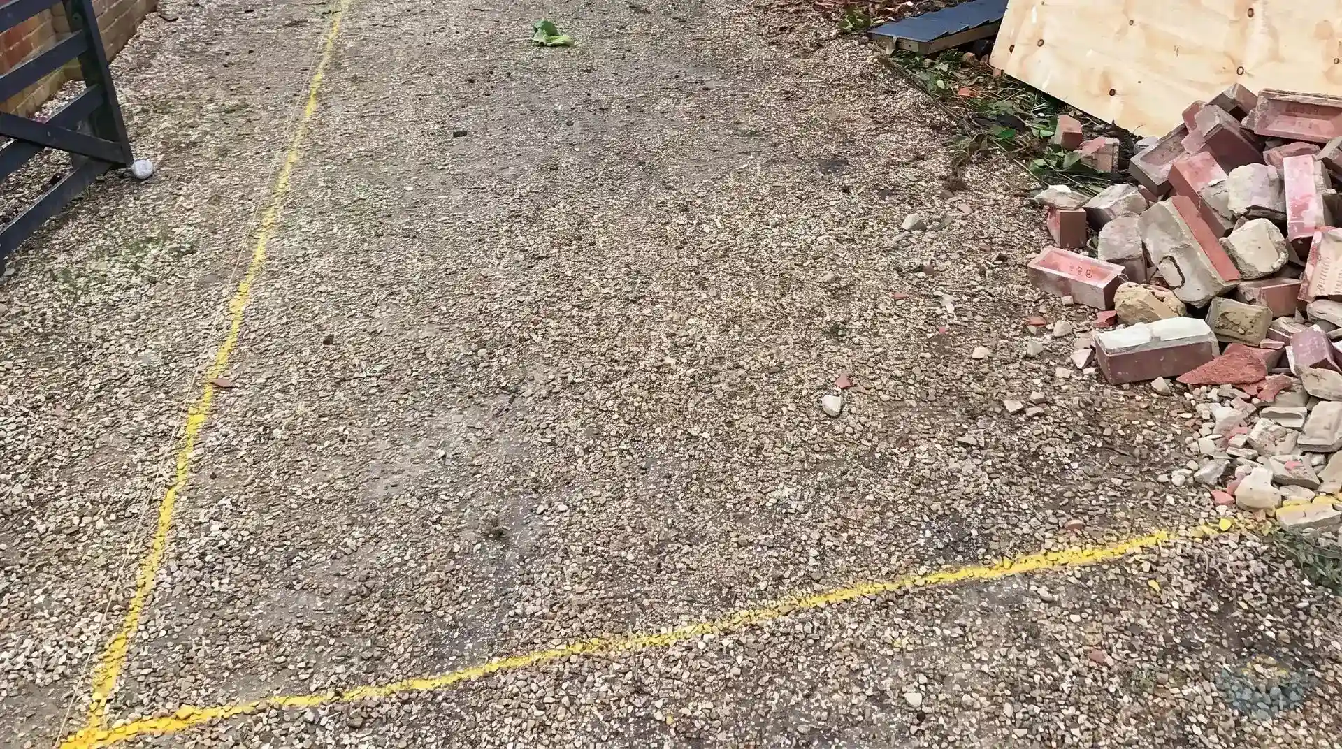 The extension footprint sprayed out in yellow line on the ground along the side and rear of a detached house, photographed in low evening light shortly before work began.