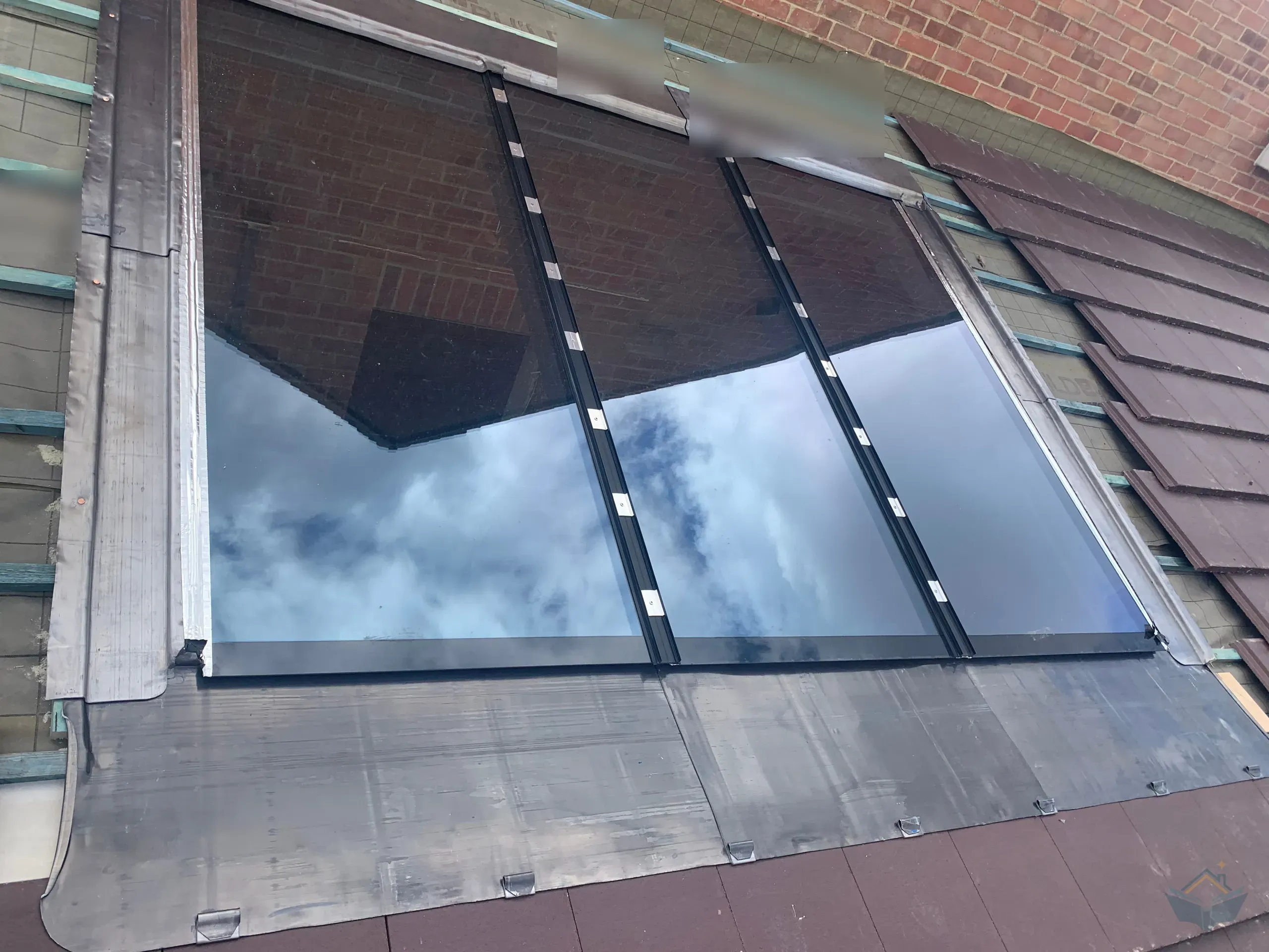 The first roof window with its fresh lead apron and side flashings, patination oil newly applied along the top edge, membrane and battens still open around it.
