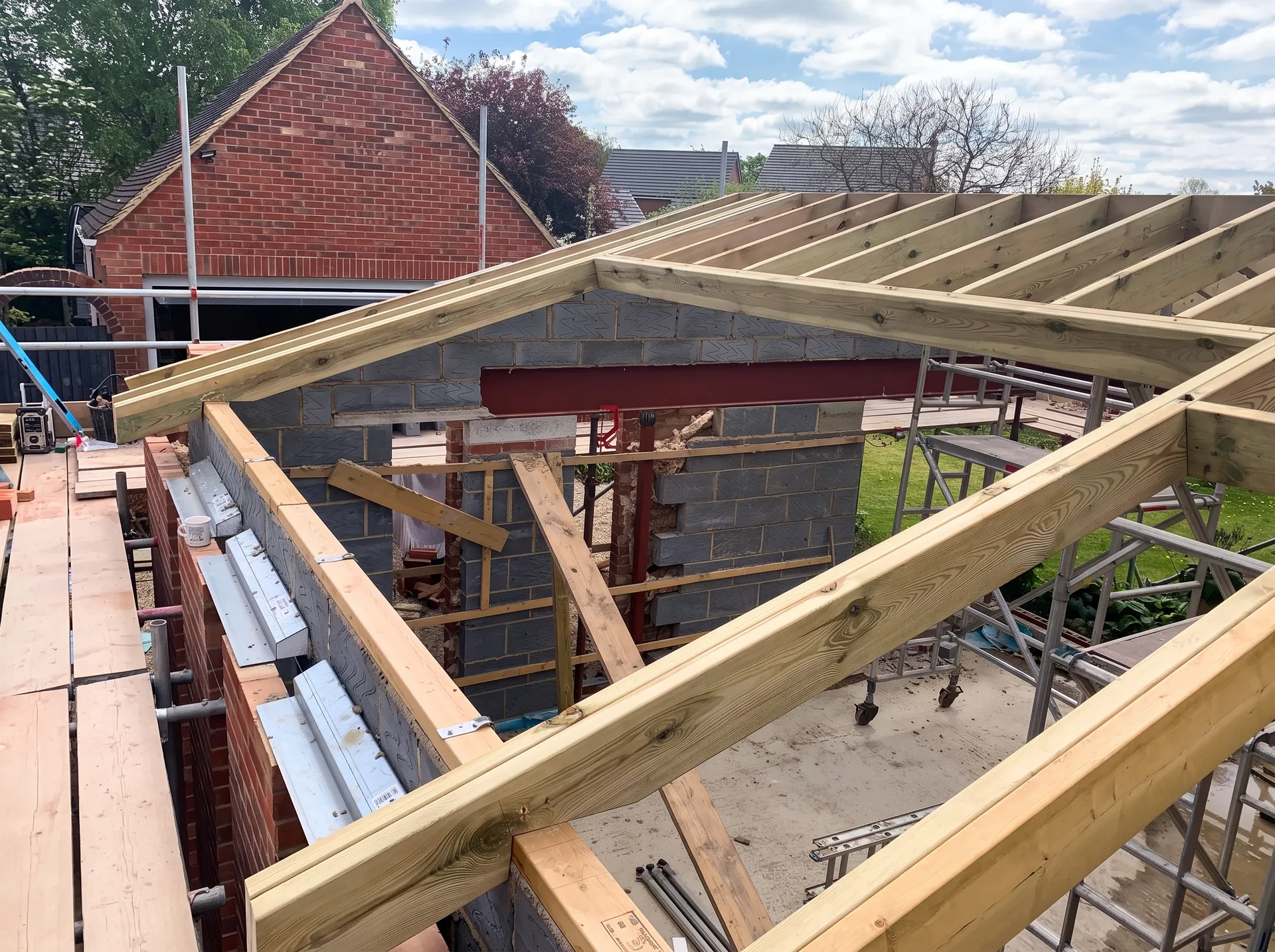 Rear of an extension under construction showing a framed rectangular aperture in the rafters for a roof window, doubled timbers, wall plate and cavity closers along the window openings.